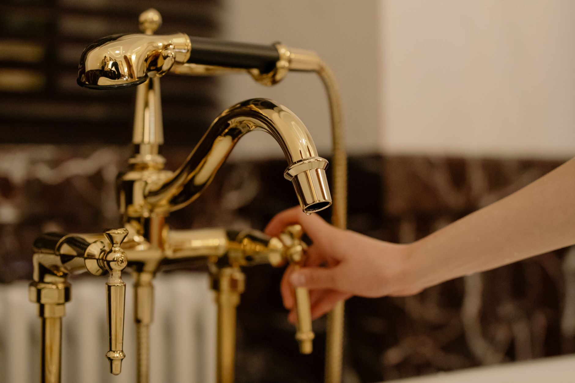 Close-up of a warm gold bathroom faucet against dark walnut paneling